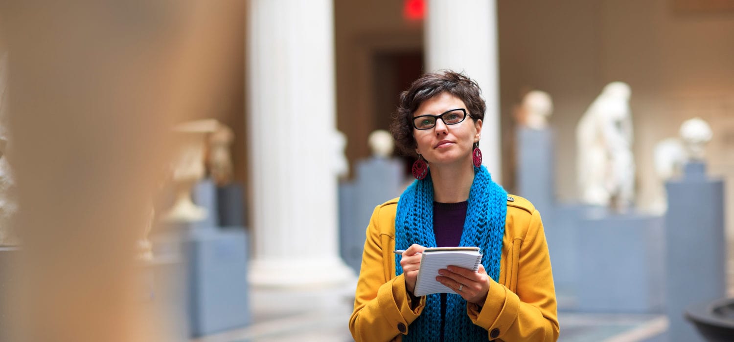 female student looking in museum with notebook