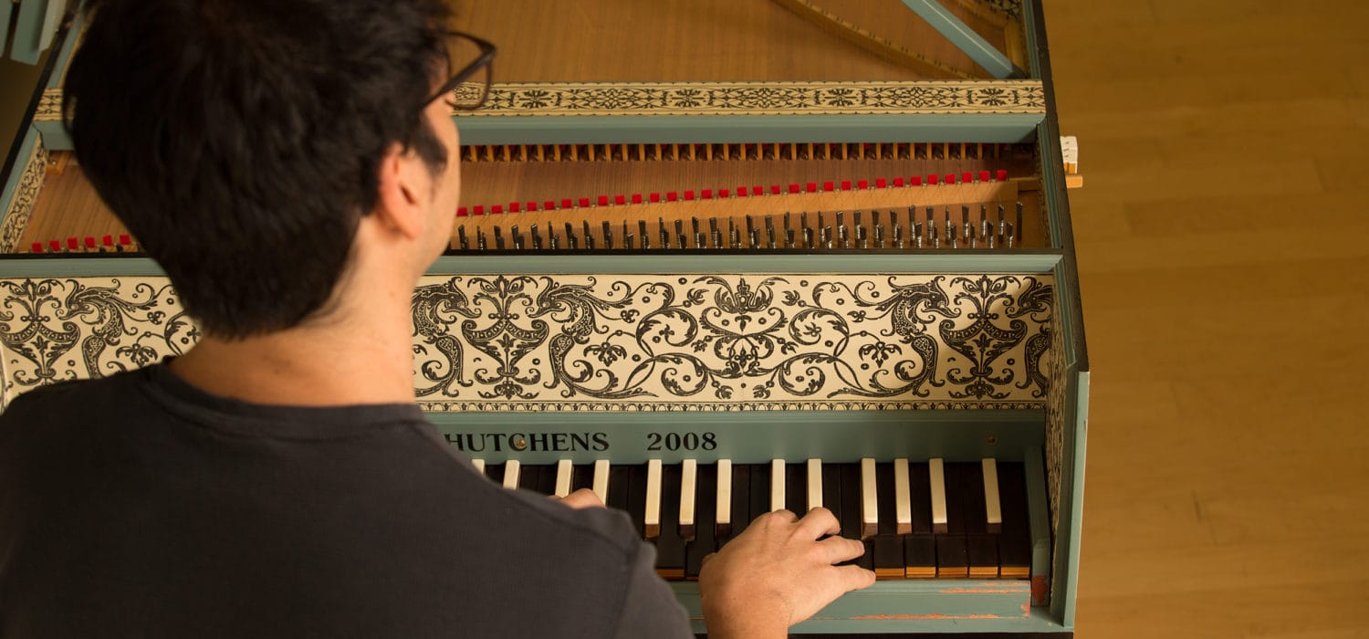 student playing a decorative harpsichord