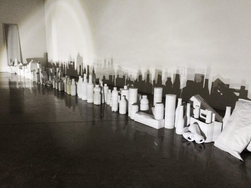 Student artwork by Chaoyi Stormy Wu, a line of white painted objects casting a shadow on a wall