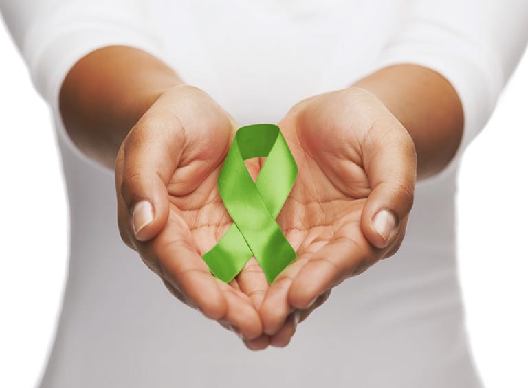 green ribbon for organ donor research in the palms of a person's hands