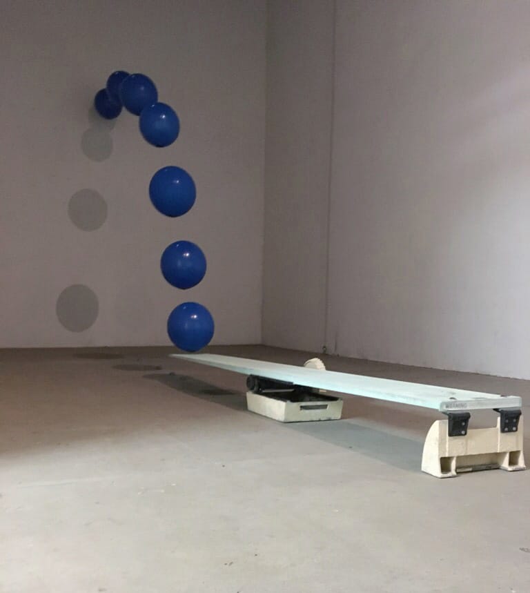 Student artwork by Rafaella Suarez, blue balls seeming to bounce off a diving board onto a wall