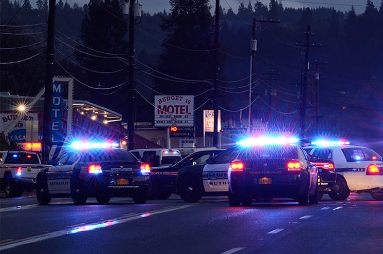 Police cars with lights going in front of a motel.