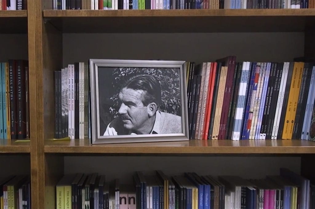 A photo of Kingsley Tufts on a bookshelf of poetry