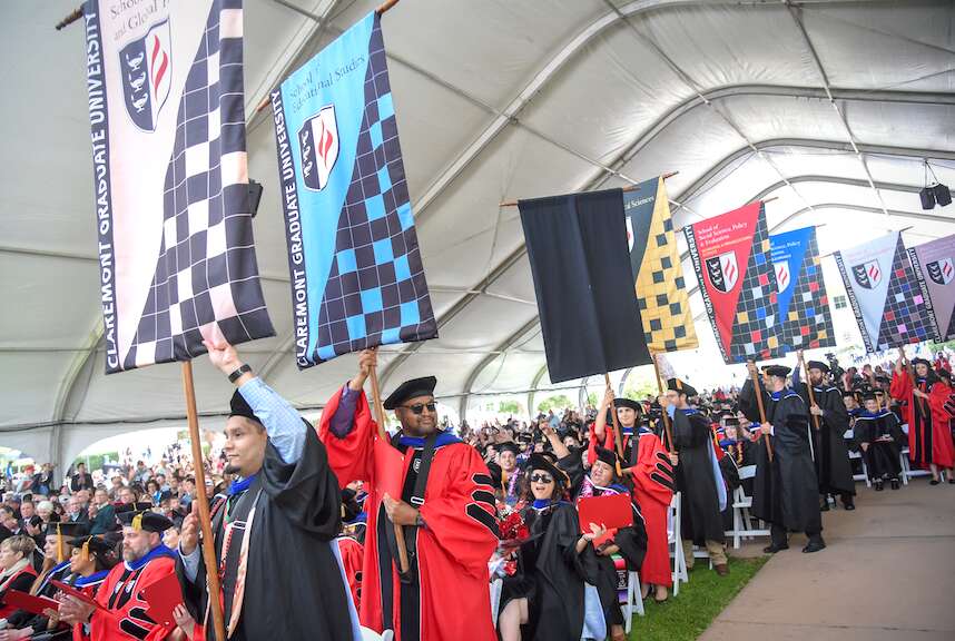 Banner carriers arrive under the big tent during CGU's Commencement.