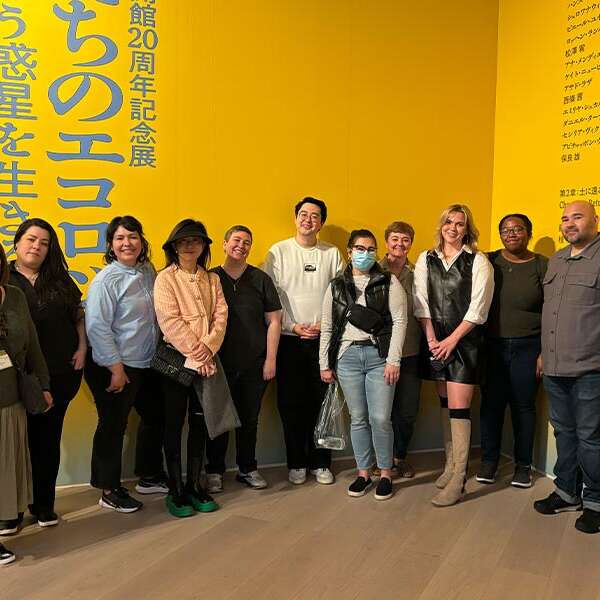 Group of students from the Drucker School of Management standing next to a yellow wall