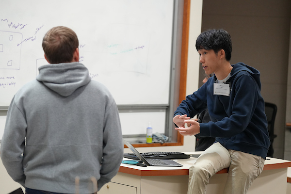 Two men talking in front of a whiteboard 
