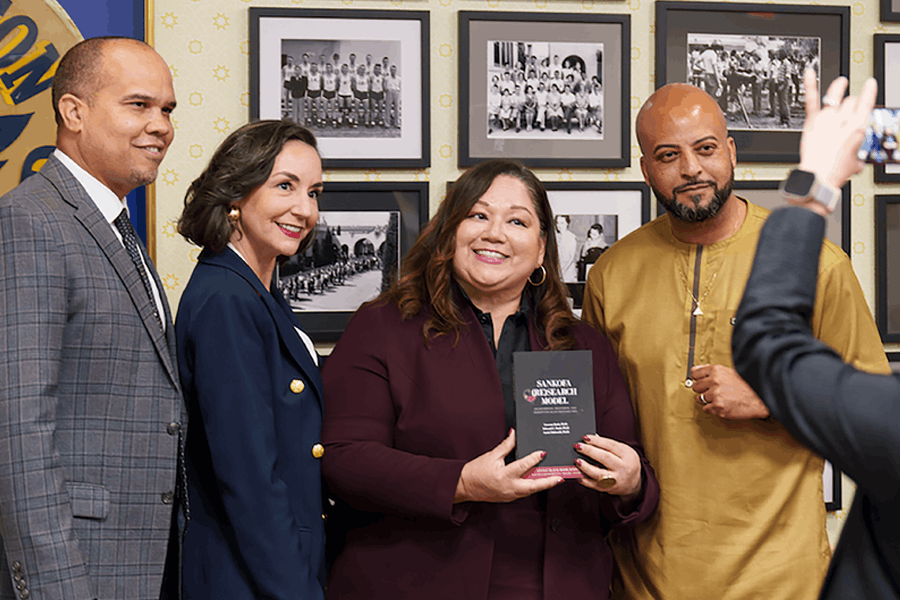 Dr. Cynthia Olivo (center) with colleagues, holding the Sankofa Research Model.