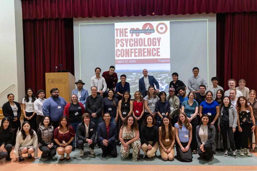 A group of students stand smiling in front of the 7c psychology conference in 2026