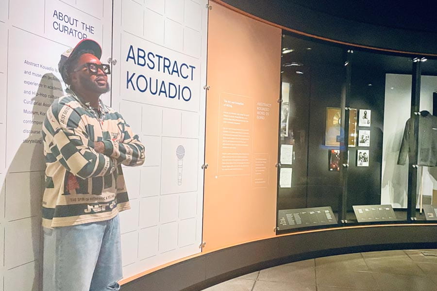 PhD student, Abstract Kouadio, stands in front of his art exhibition